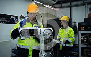 A big welding robot is being inspected and controlled by a robotics engineer. After the machine has been used for the specified