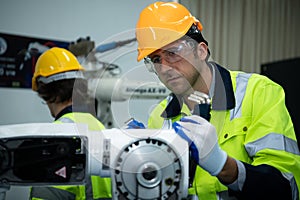 A big welding robot is being inspected and controlled by a robotics engineer. After the machine has been used for the specified