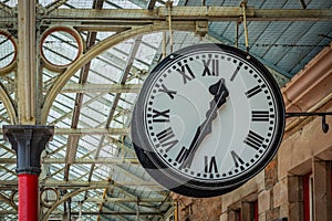 Big white clock with black numbers in the train station hall