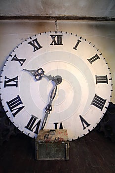 Big white clock with Roman dial stands in room