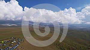 Big white clouds over green hills and mountains.