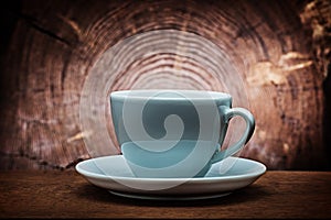 Big white coffee cup for capuchino on vintage wood background with cross cut of tree trunk