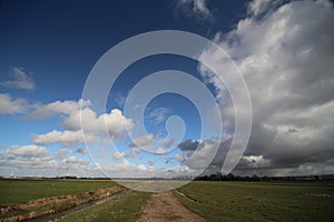 Big white and grey clouds and blue sky in wide angle view over the meadows of the Zuidplaspolder