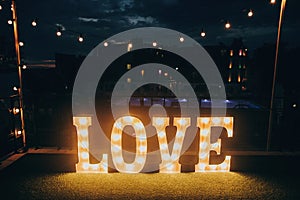 Big white love letters in light bulbs for photo booth at wedding