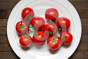 Big white plate with red washed tomatoes on it