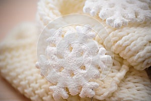 Big white snowflake on white knitted scarf background