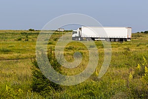 The big white truck goes across the field.