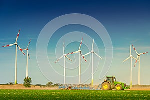 Big wind turbines to generate electrical power, green ecofriendly energy at blue sky standing at farm green field with working