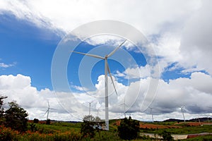 Big wind wheel in the blue sky full of cloud and the green hill