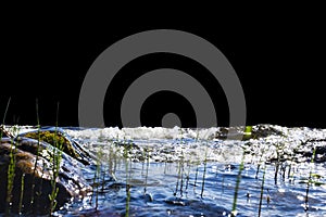 Big windy waves splashing over rocks. Wave splash in the lake isolated on black background. Waves breaking on a stony beach