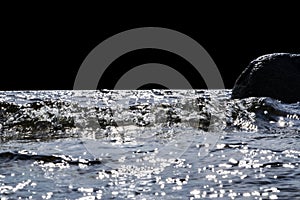 Big windy waves splashing over rocks. Wave splash in the lake isolated on black background. Waves breaking on a stony beach