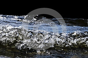 Big windy waves splashing over rocks. Wave splash in the lake isolated on black background. Waves breaking on a stony beach