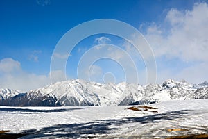 Big winter snowy mountains above which clouds fly by and snow sparkles. Winter picturesque landscape