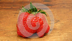 A big wonky red strawberry on a rustic wooden table top