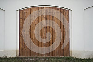 Big wooden barn gate. Monumental farm door, two timber leaf, closed brown gateway with planks and nails