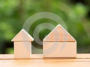 Big wooden home and small wooden home on floor with green background. Home loan or building home concept