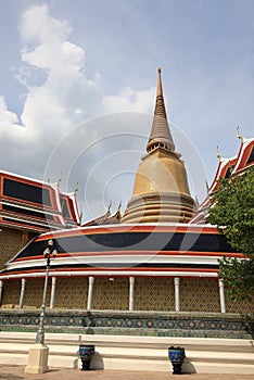 The big yellow ancient pagoda appear over the roof of Buddhist temple with beautiful blue sky in Bangkok, Thailand