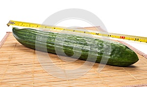 Big yellow centimeter measuring a green cucumber