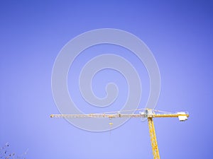 Big yellow crane working on a construction site in the nice clear sky.
