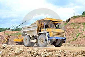 Big yellow dump truck working in the limestone open-pit. Loading and transportation of minerals in the dolomite mining quarry.