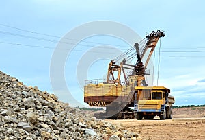 Big yellow dump truck working in the limestone open-pit. Loading and transportation of minerals in the dolomite mining quarry.