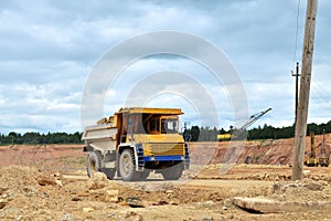 Big yellow dump truck working in the limestone open-pit. Loading and transportation of minerals in the dolomite mining quarry.