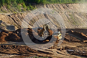 Big yellow dump truck working in an sand open-pit. Mining quarry for the production of crushed stone, sand and gravel for use in