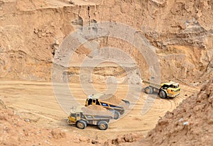 Big yellow dump trucks working in the open-pit.