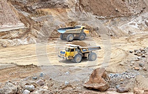 Big yellow dump trucks working in the open-pit.