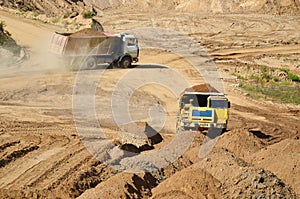 Big yellow dump trucks working in the open-pit.