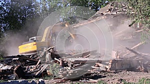 Big yellow excavator breaks down old wooden house