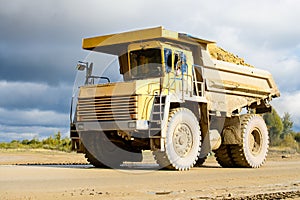 Big yellow mining truck transporting materials down a dirt road