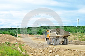 Big yellow mining truck working in the limestone open-pit. Loading and transportation of minerals in the dolomite mining quarry.