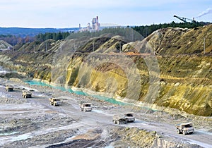 Big yellow mining trucks working in the limestone open-pit. Loading and transportation of minerals in the chalk open-pit.