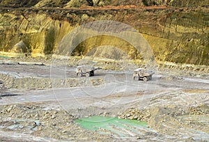 Big yellow mining trucks working in the limestone open-pit. Loading and transportation of minerals in the chalk open-pit