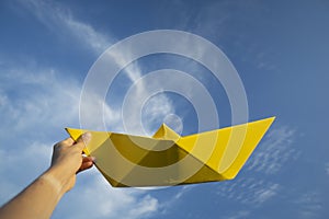 Big yellow paper boat with blue sky and white clouds