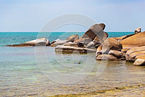 Big yellow rocks in the sea against the blue sky. Floating man in mask and flippers. Thailand. Samui. Gulf of Thailand. Lamai