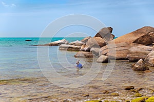 Big yellow rocks in the sea against the blue sky. Floating man in mask and flippers. Thailand. Samui. Gulf of Thailand. Lamai