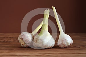 Big young garlic heads on a brown wooden plank table. Closeup