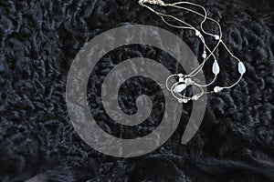 Bijouterie. the necklace lies on a black sheep skin. contrast. the stones shimmer from the natural sun color