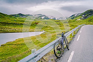 Bike with active equipment at norway mountains scene. Bicycle On Mountain. Bicycle Parked On road Against Mountains