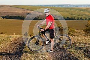 Bike adventure travel photo. Bike tourist rides on the country road. Sunset on background.