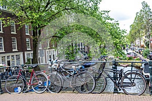 Bike on a bridge over canal, boat on water. Traditional house brick facade. Amsterdam, Netherlands