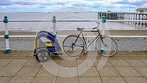 Bike with child cycle trailer, secured to railing on the sea fro