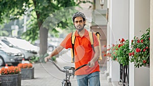 Bike, city and food delivery concept. Courier with beard, in helmet and bag, walks with bicycle down the street