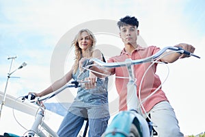 Bike, couple and carbon footprint with a man and woman riding a bicycle outdoor on a blue sky background from below