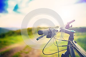 Bike handle bar at sunset on mountain trail. details of sport activities