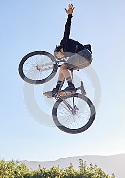 Bike jump, man and sport outdoor with biker and fitness, adrenaline and dangerous stunt with blue sky and sunshine