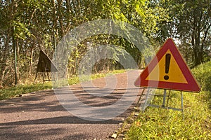 Bike lane in the countryside with trees and street lights and a danger sign on the ground on a clear day in summer