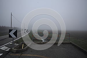 Bike lane on a foggy day next to a trench with water on a foggy day in the italian countryside